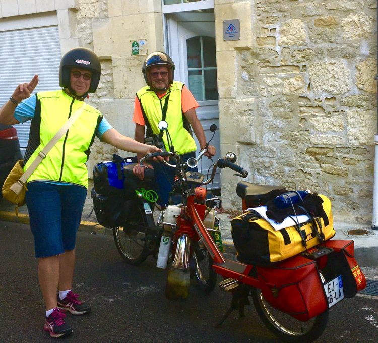 Groupe de cyclistes vintage sur Solex, prêts à partir depuis Cognac, exprimant la satisfaction et l’esprit de découverte