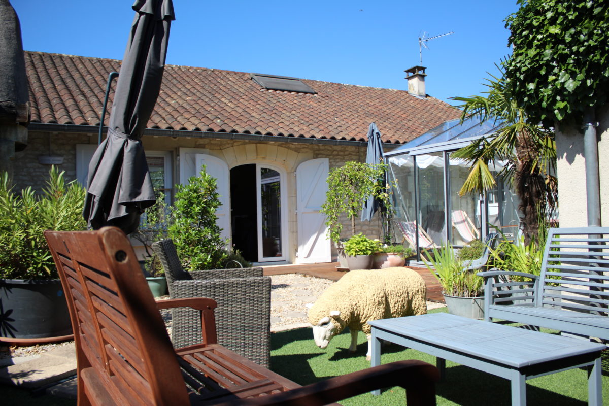 Terrasse ensoleillée à Suite en Terrasse à Cognac, salon de jardin et mouton mascotte, illustration d’un séjour authentique et éco-responsable